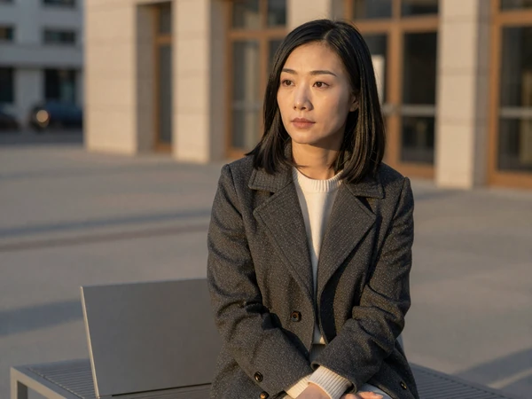 Female ER doctor sitting thoughtfully on a city bench at golden hour